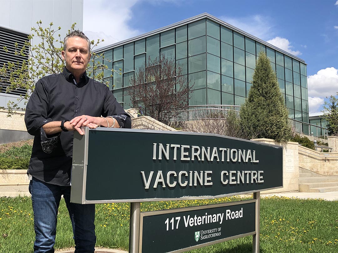 man stands beside 'International Vaccine Centre' sign