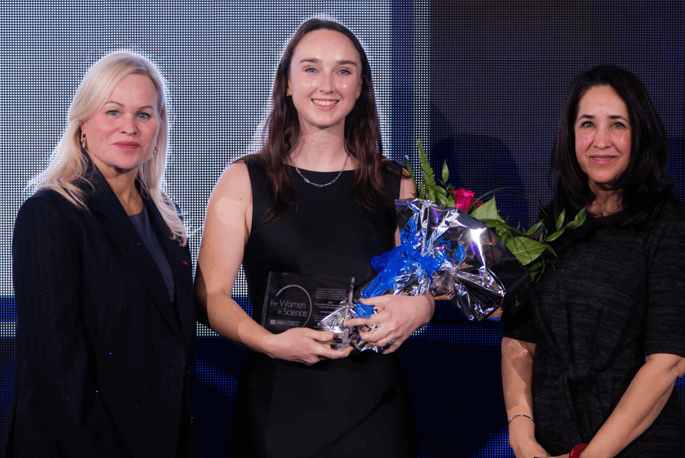 three women on stage with an award