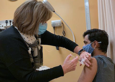 a woman inserts a needle into a man's arm